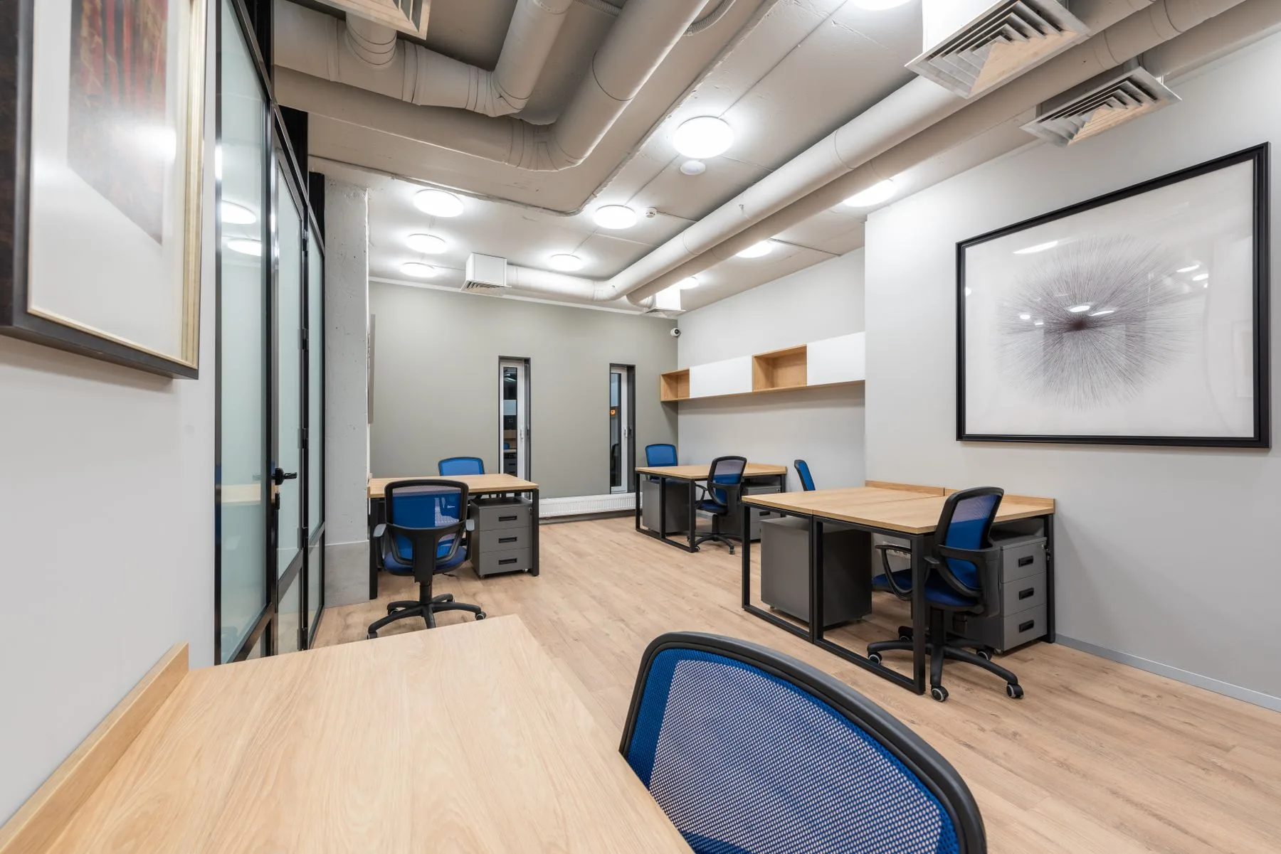 Contemporary office interior with desks and sculptural wall art.