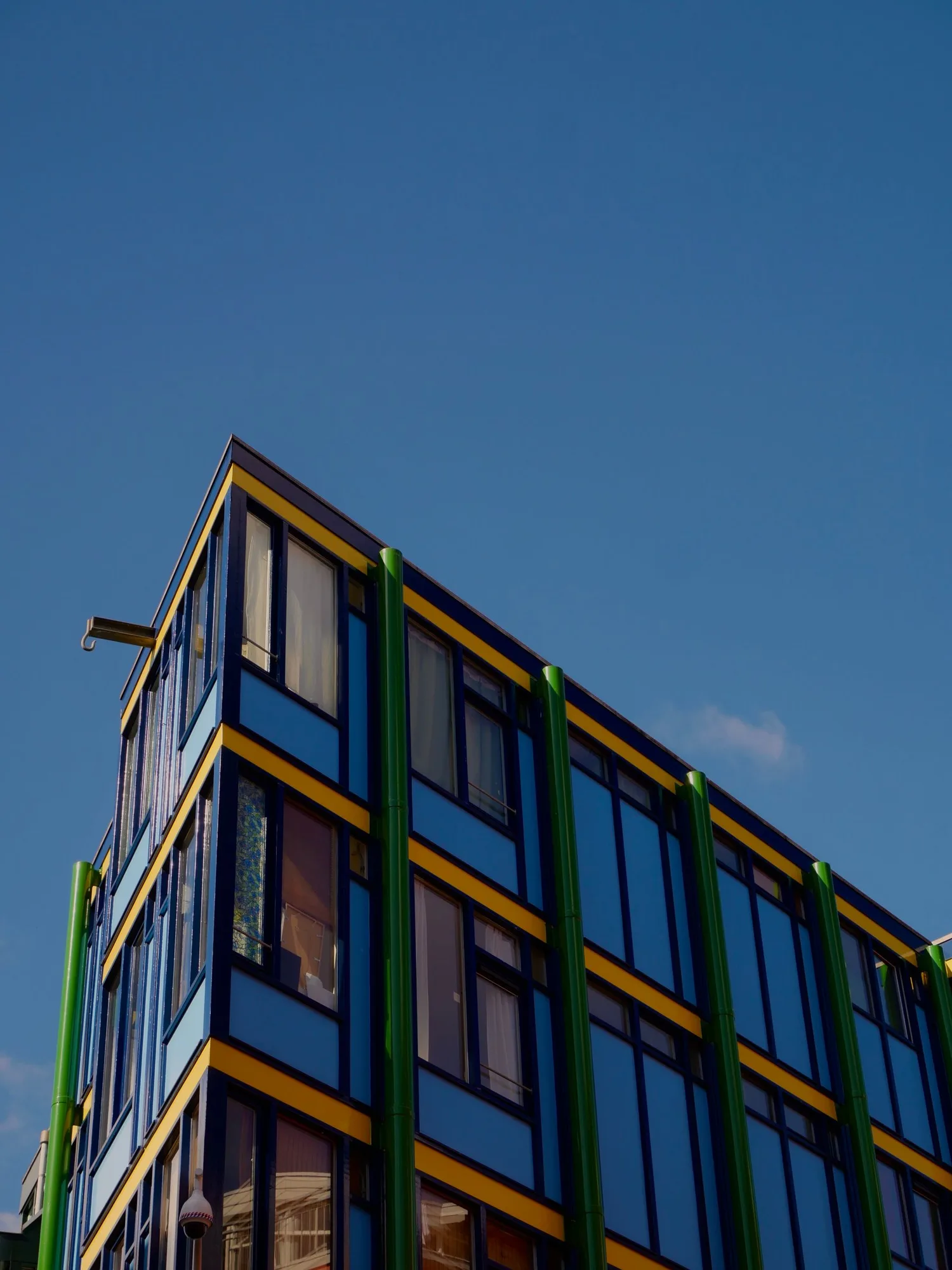 A contemporary building with colorful glass panels against a clear sky.