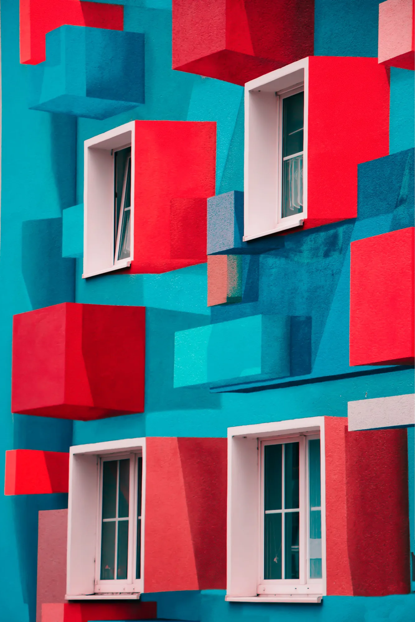 Geometric facade with teal and red projecting volumes.
