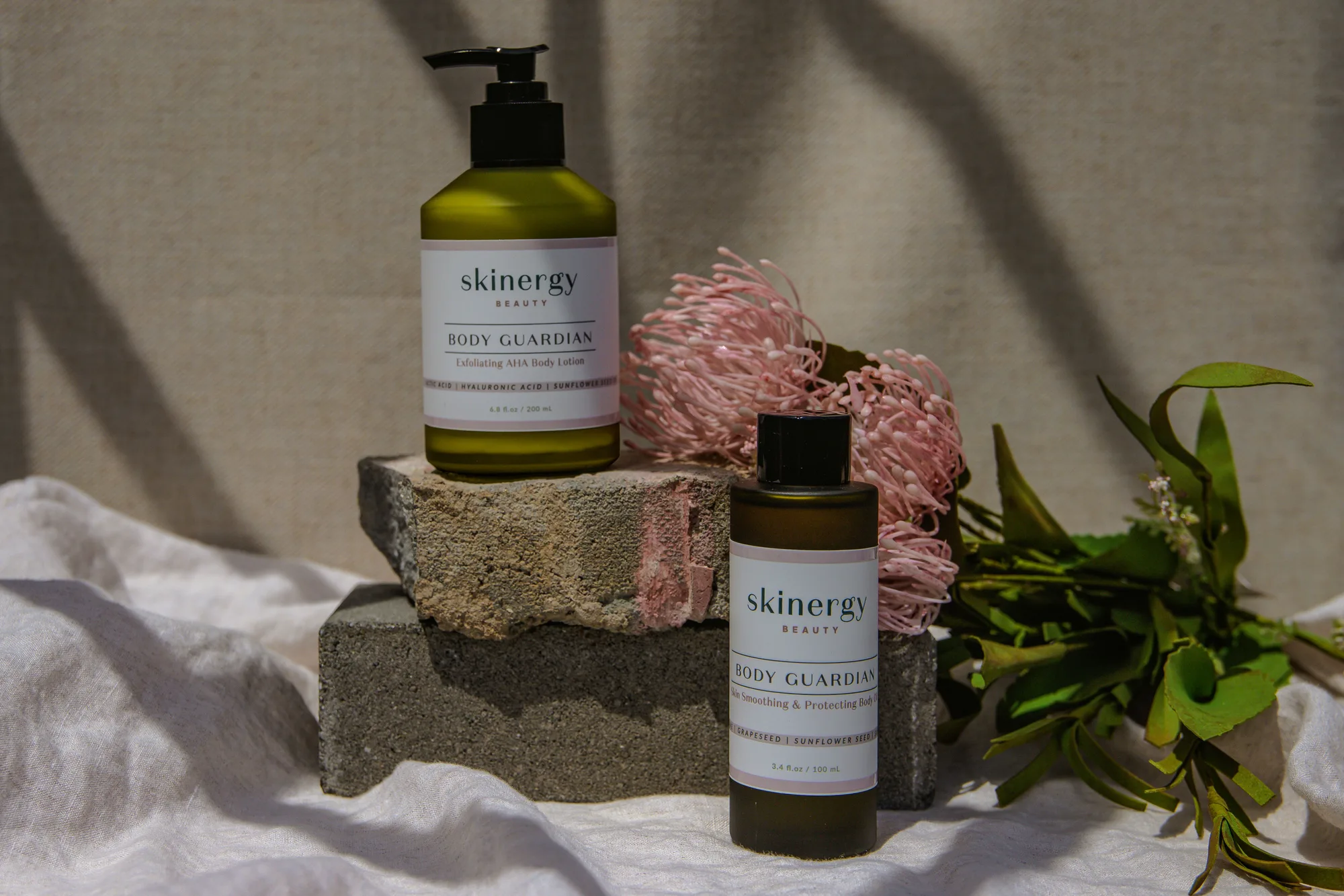 Skincare bottles and flowers on stone plinths