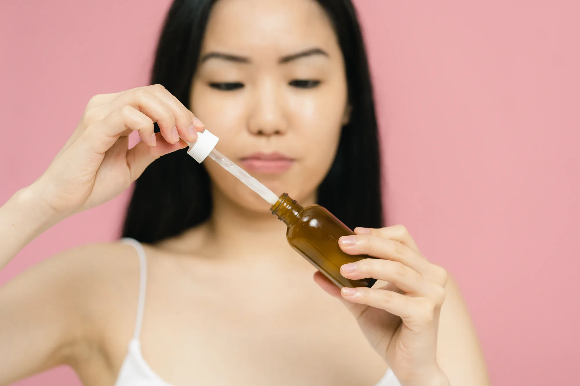 Hands holding a skincare bottle and dropper