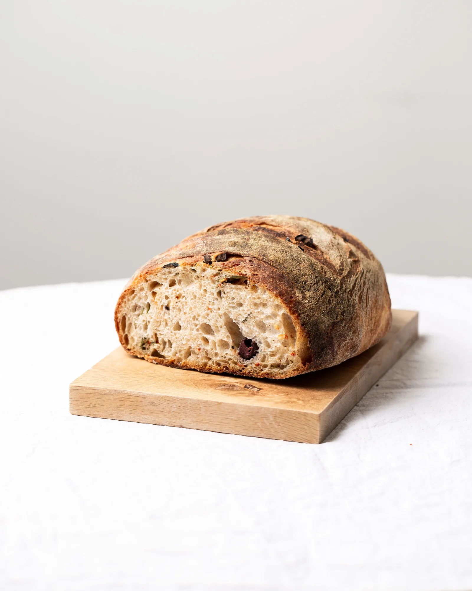 An artisan loaf of bread on a wooden board against a plain background