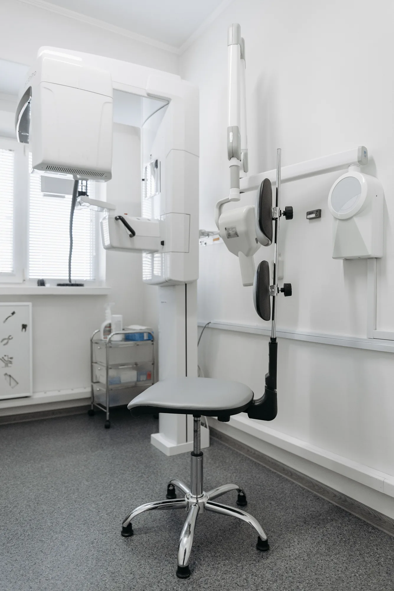 A dental imaging machine and a stool in a bright clinic