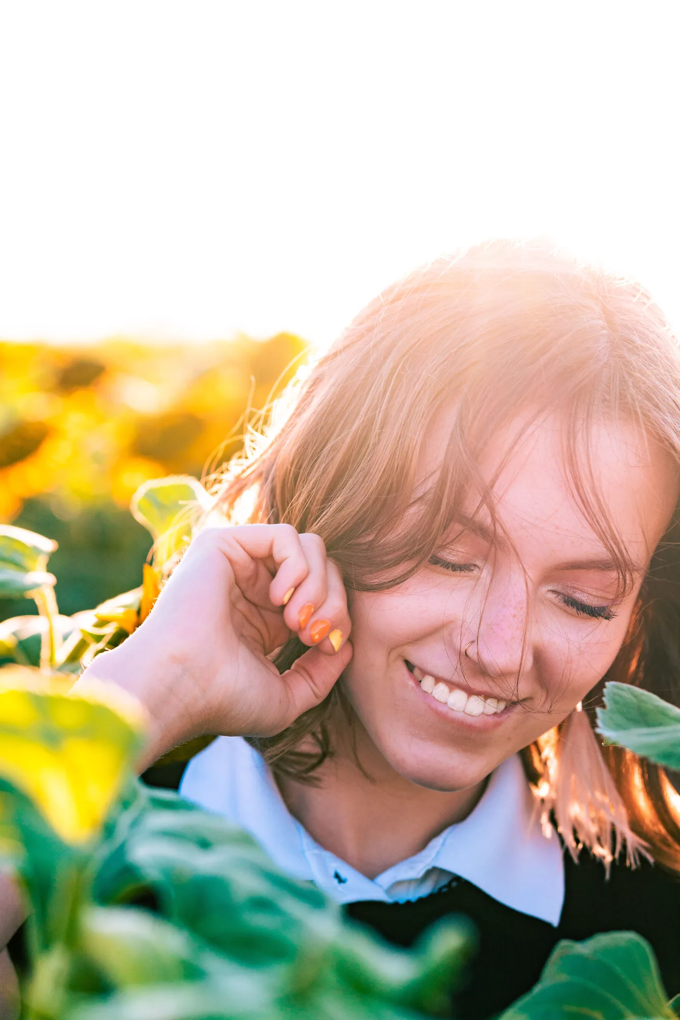 A smiling woman outdoors among green leaves