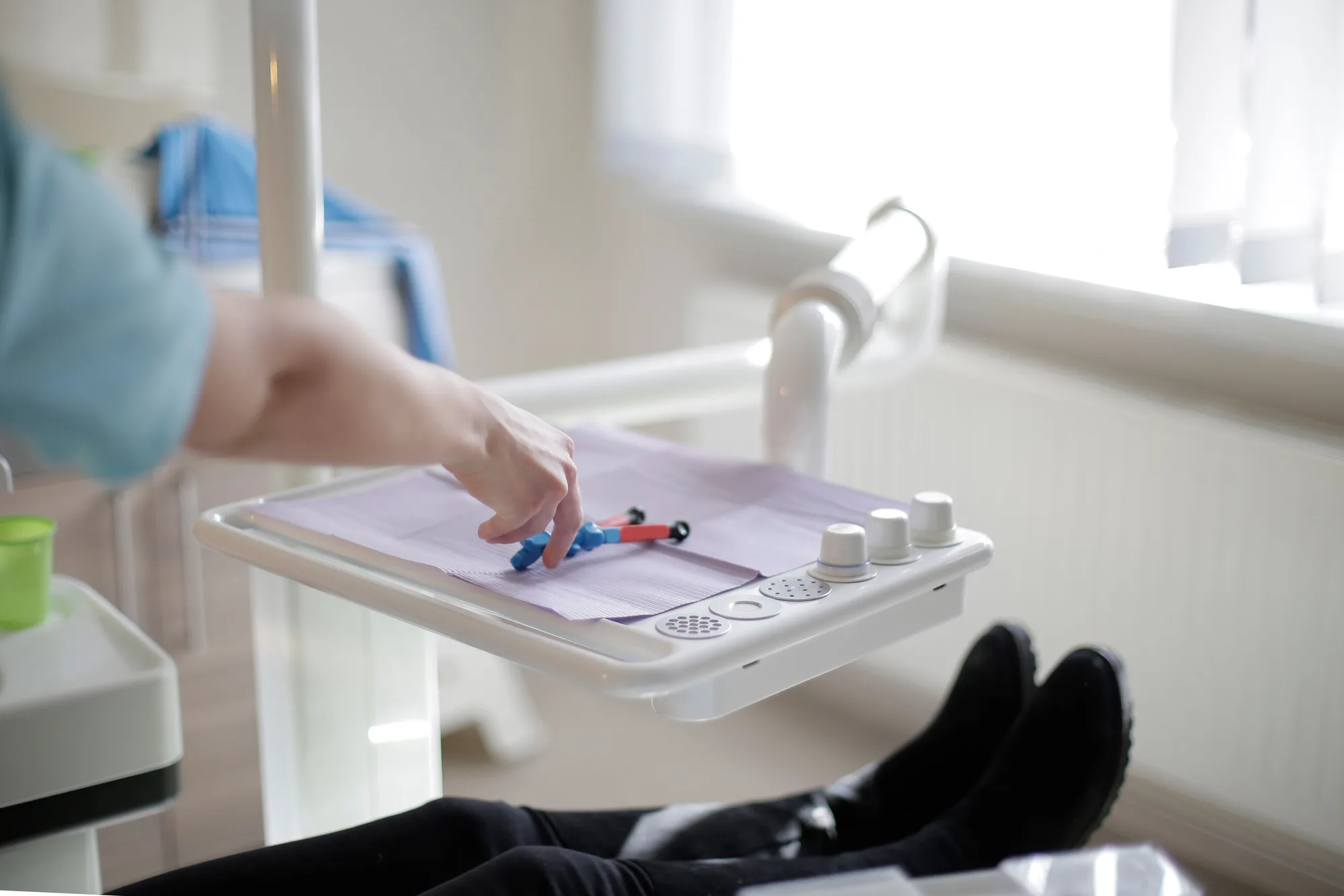 A gloved hand operating a dental equipment control panel beside a patient