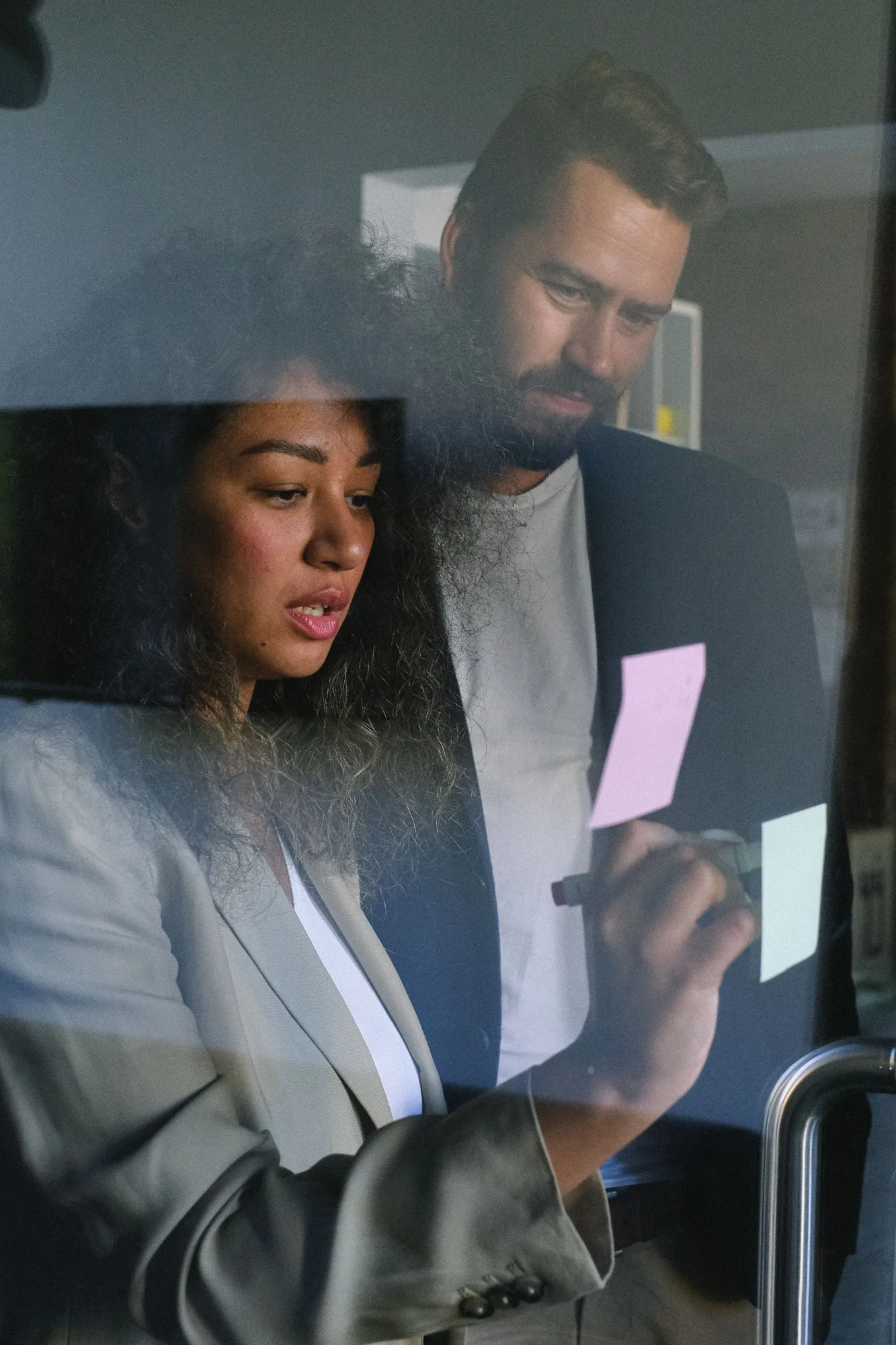 Colleagues planning together with notes on a glass board