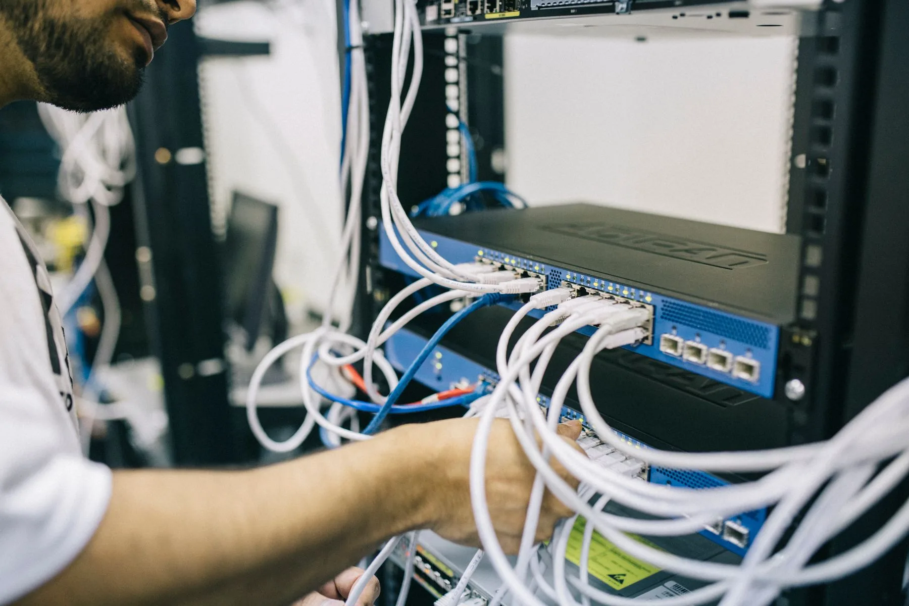 Hands arranging network connections in a server rack