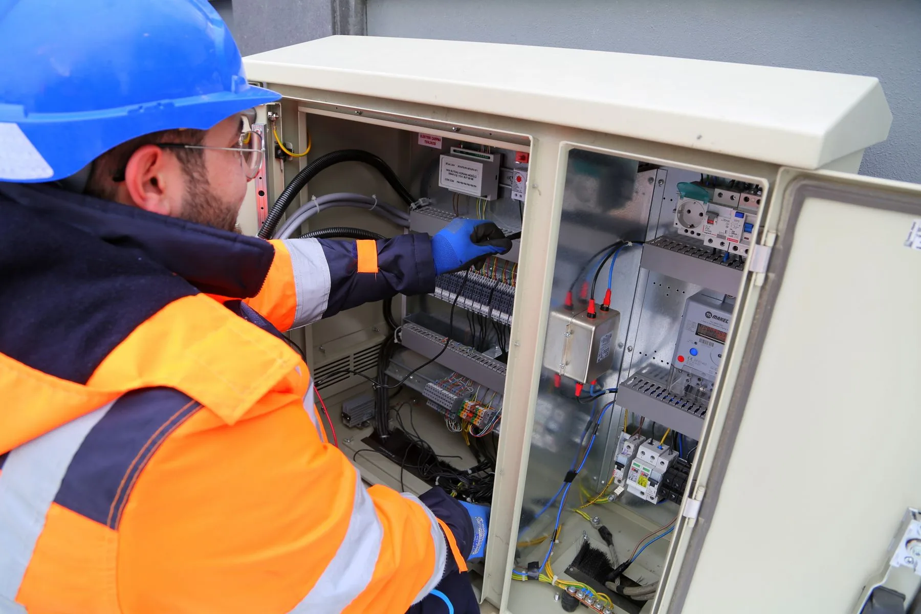 Electrician working beside an electrical control panel