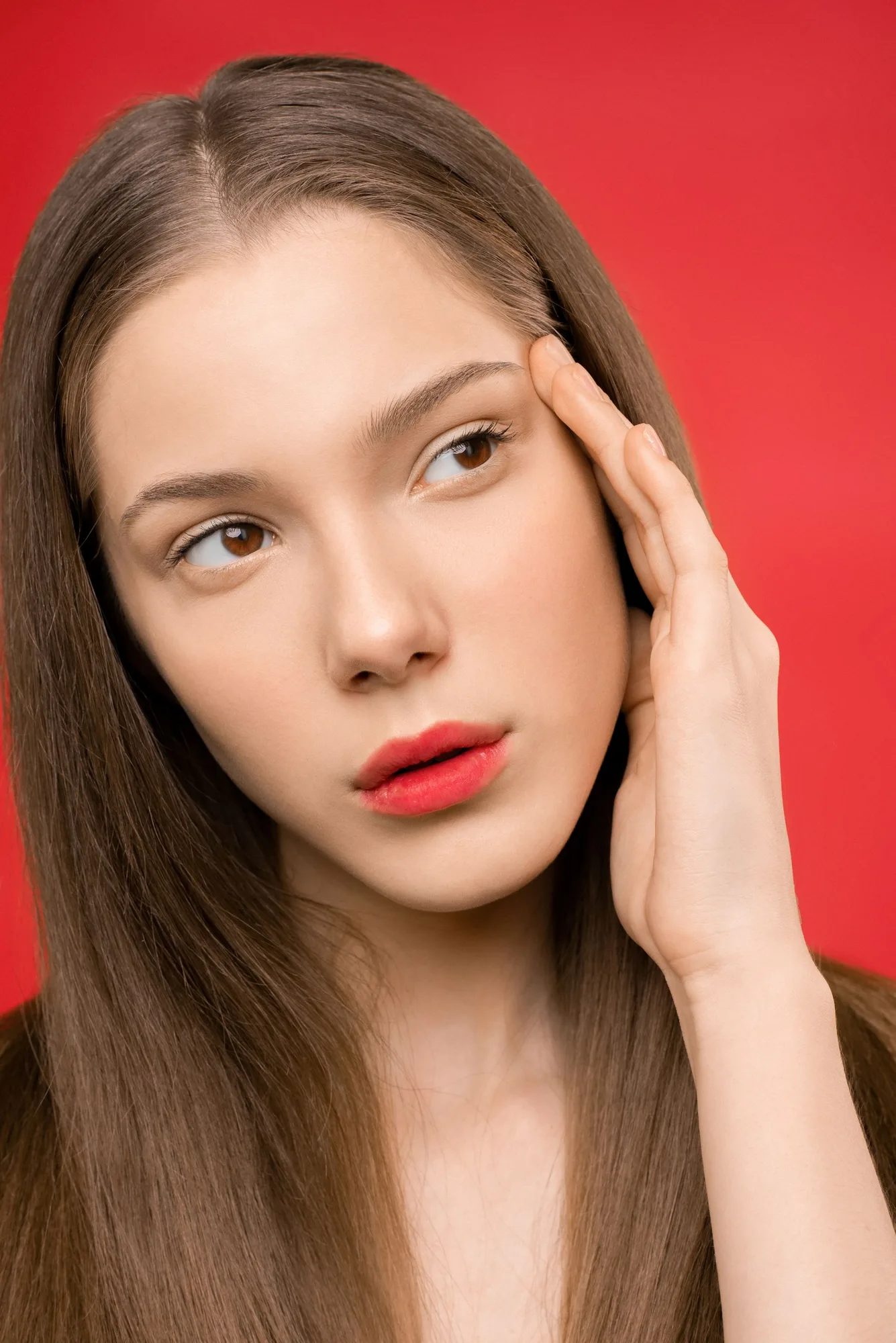 Portrait with red lipstick against a saturated red studio background.