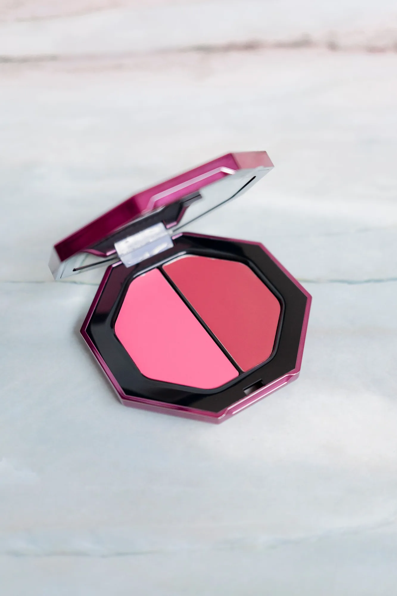 Open pink blush compact on a crisp white surface.