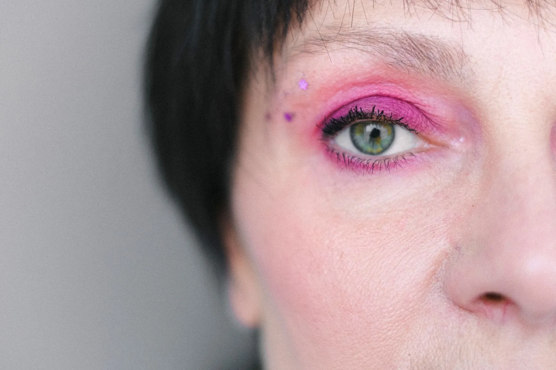 Close-up eye makeup with a bright pink graphic line.