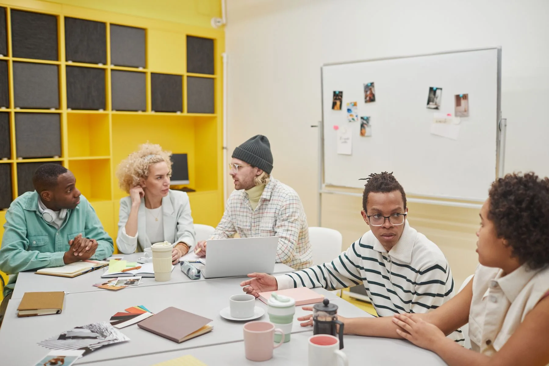 A creative team sharing ideas around a table in a bright studio.