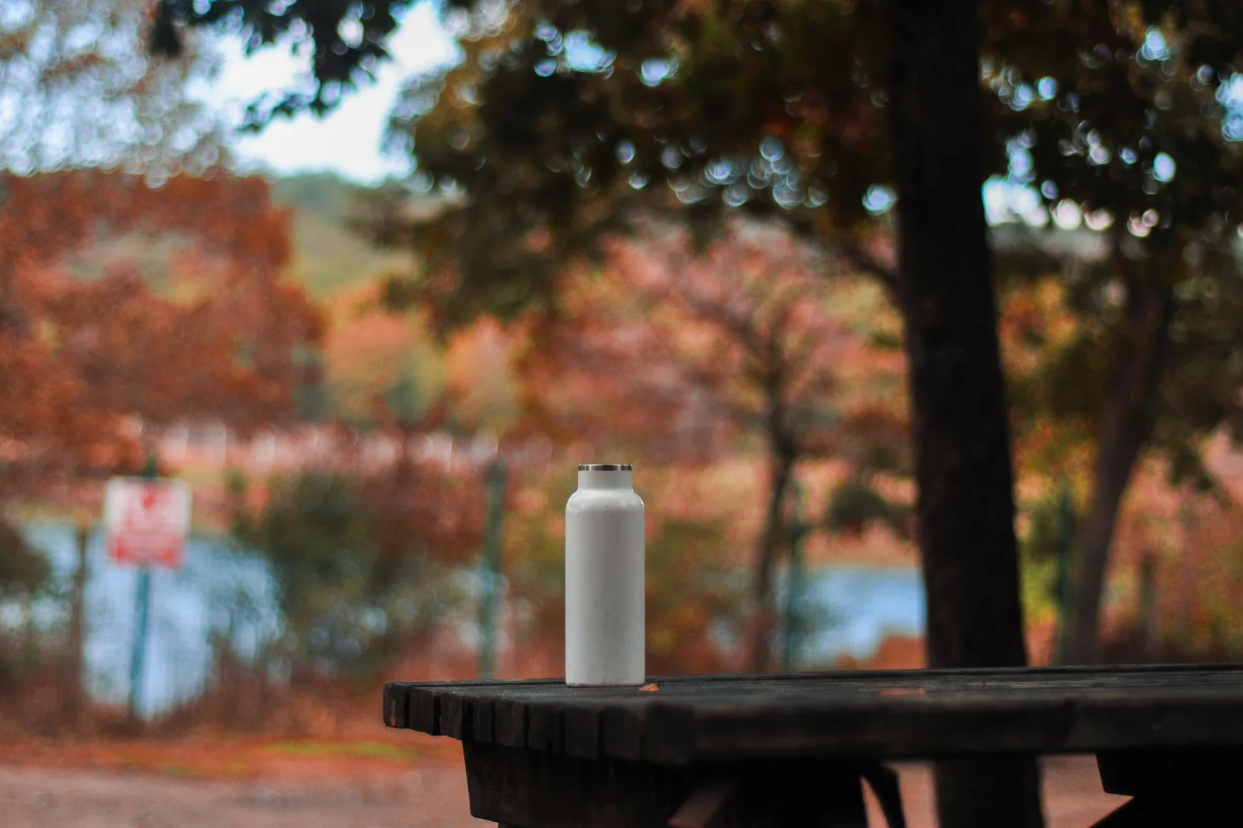 Stainless steel water bottle on a wooden picnic table outdoors