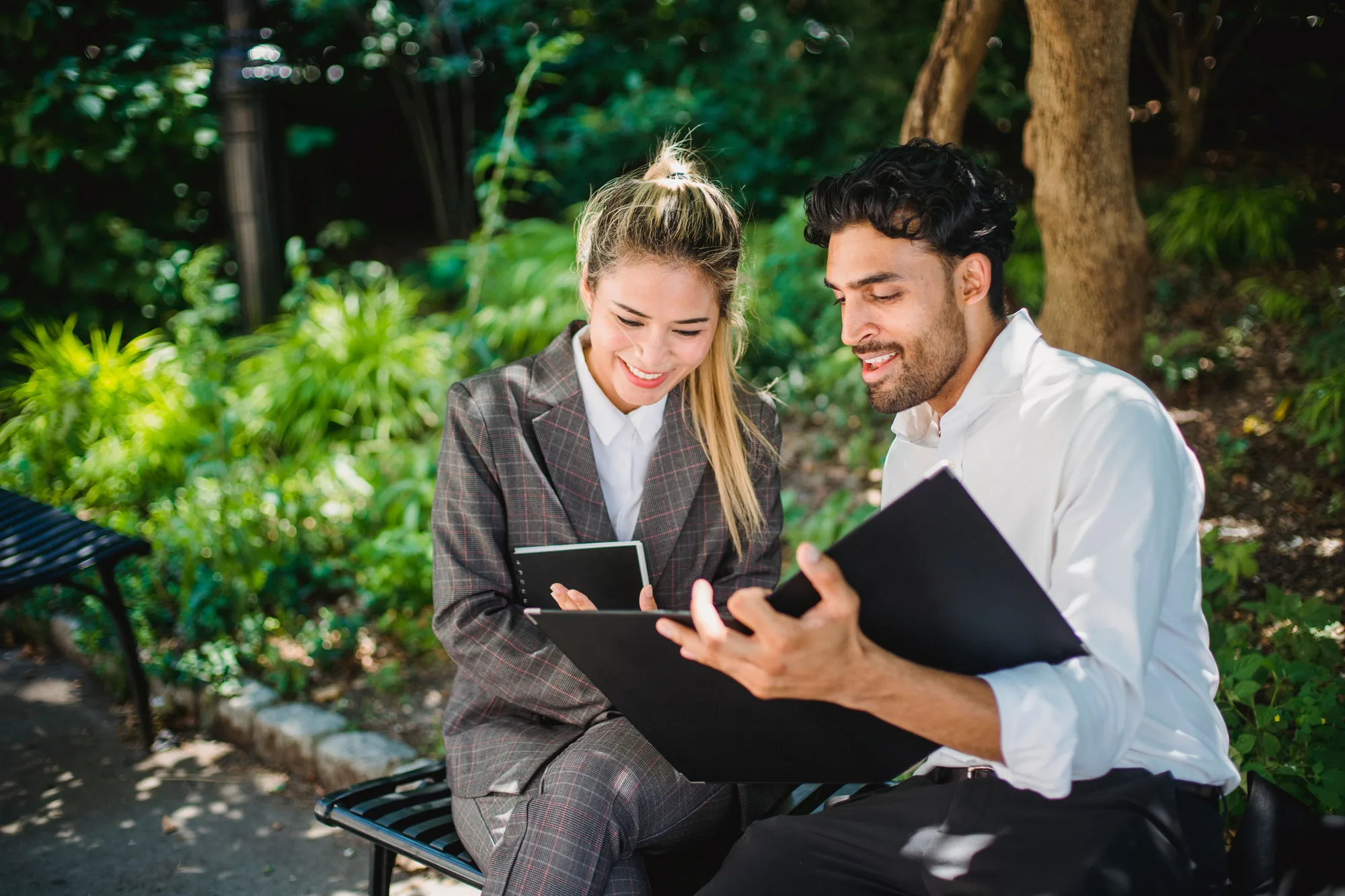 Two professionals reviewing documents while sitting outdoors