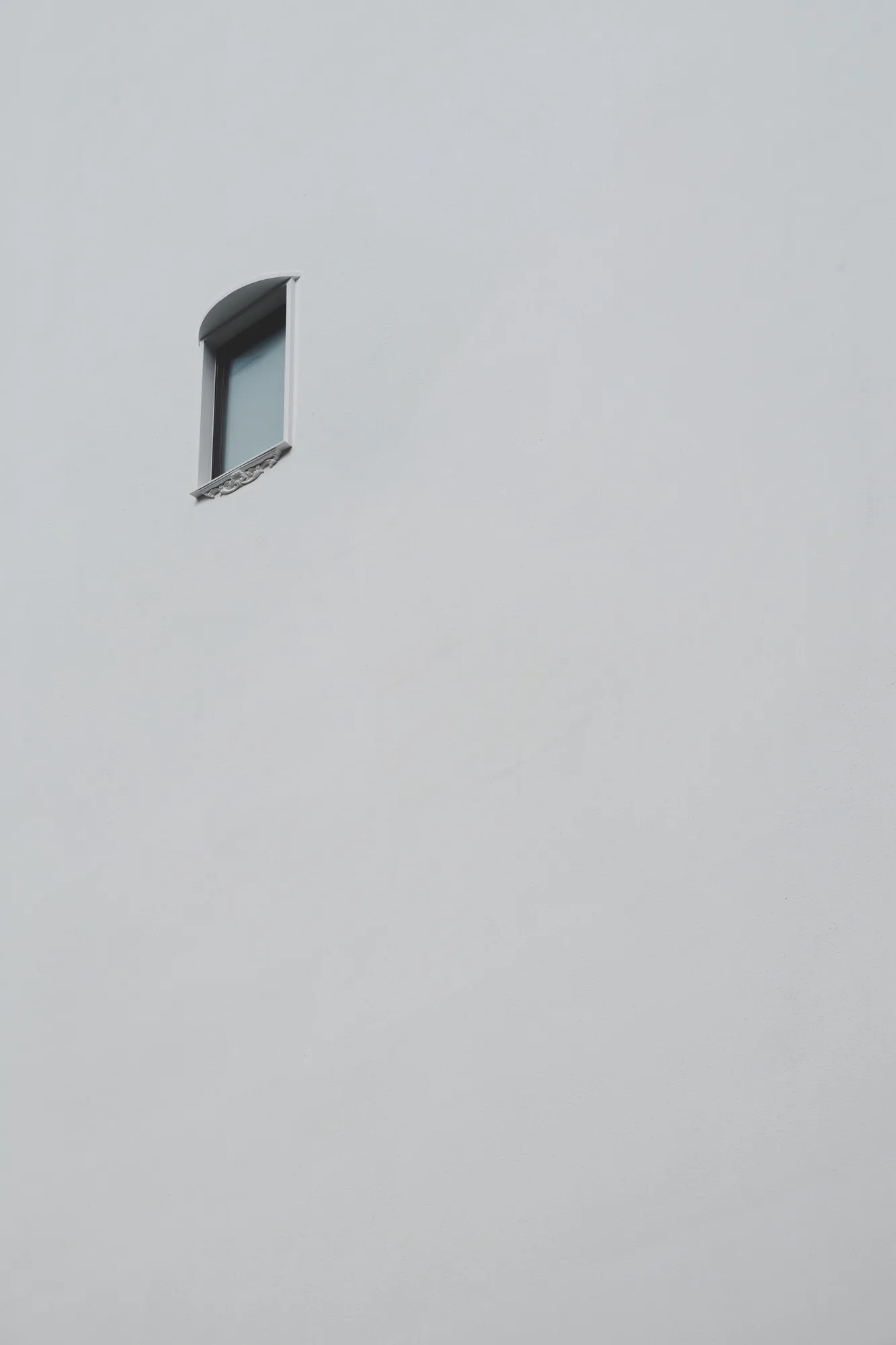 A single window in a simple white wall