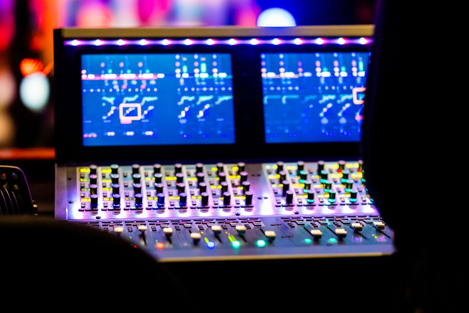 Illuminated controls on a professional audio mixing desk.
