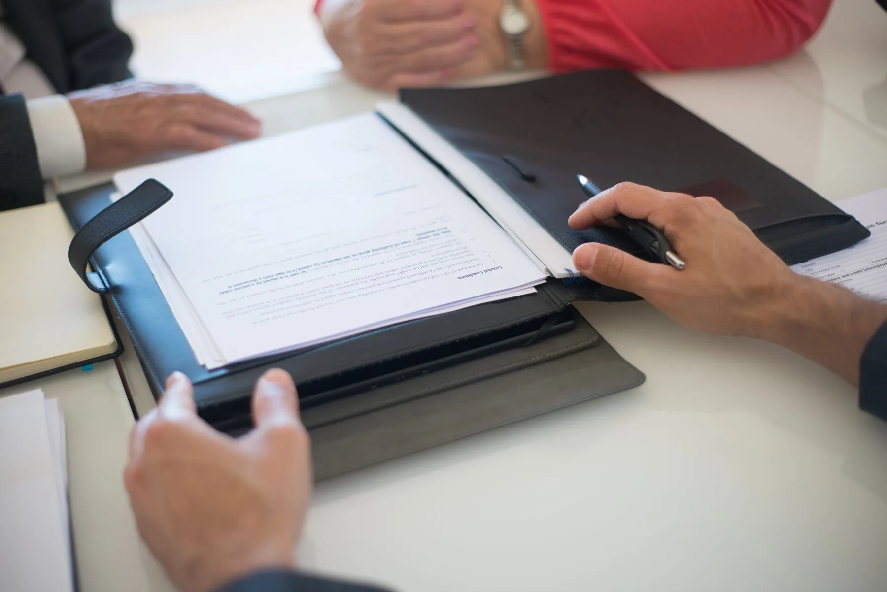A close view of hands discussing printed documents across a table.