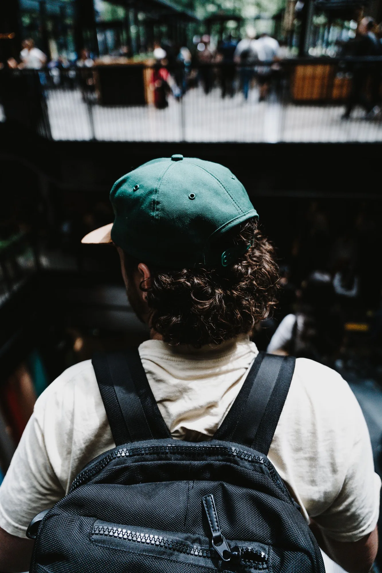 Person wearing a black backpack and green cap in the city