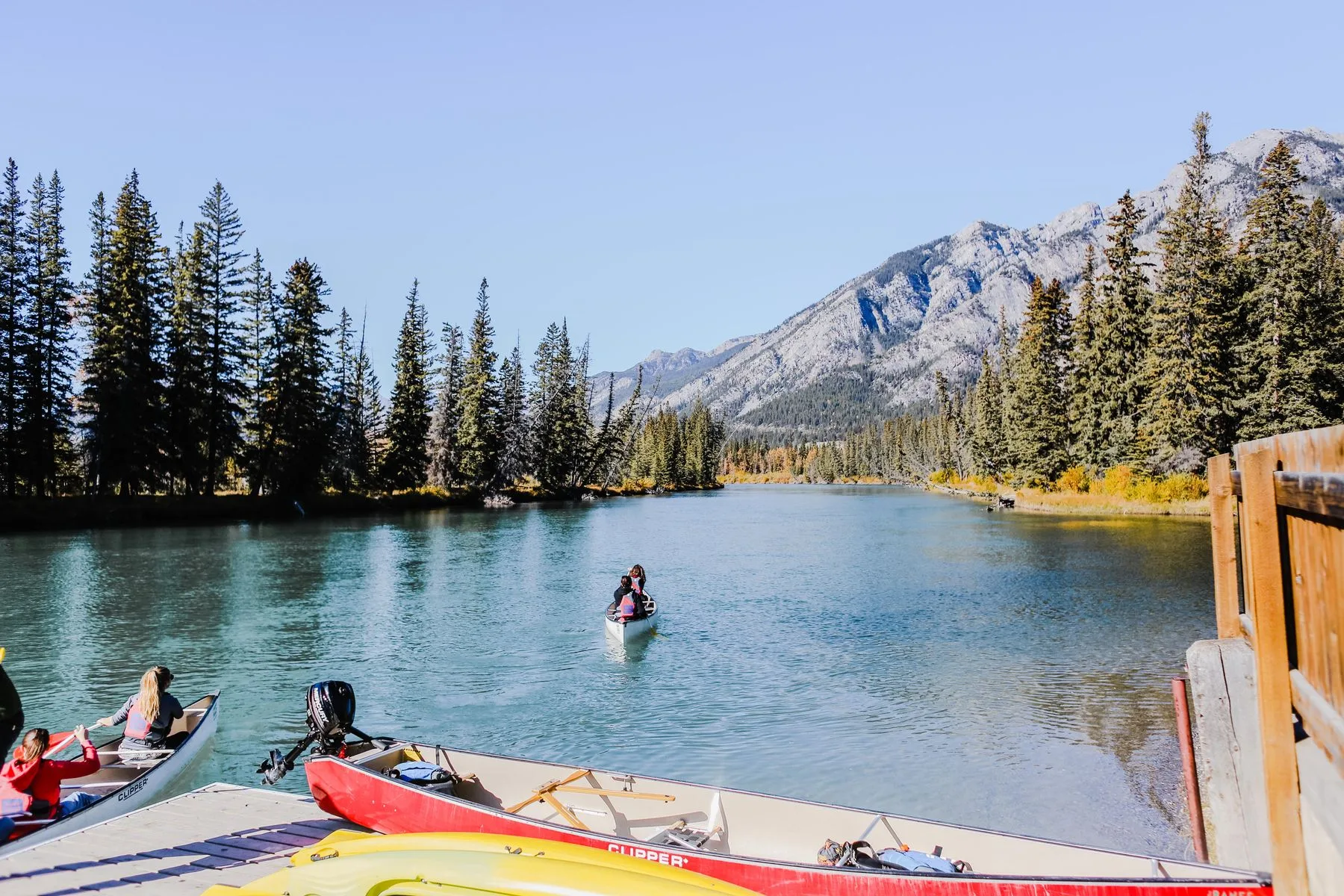 A canoeist on a still lake surrounded by forest