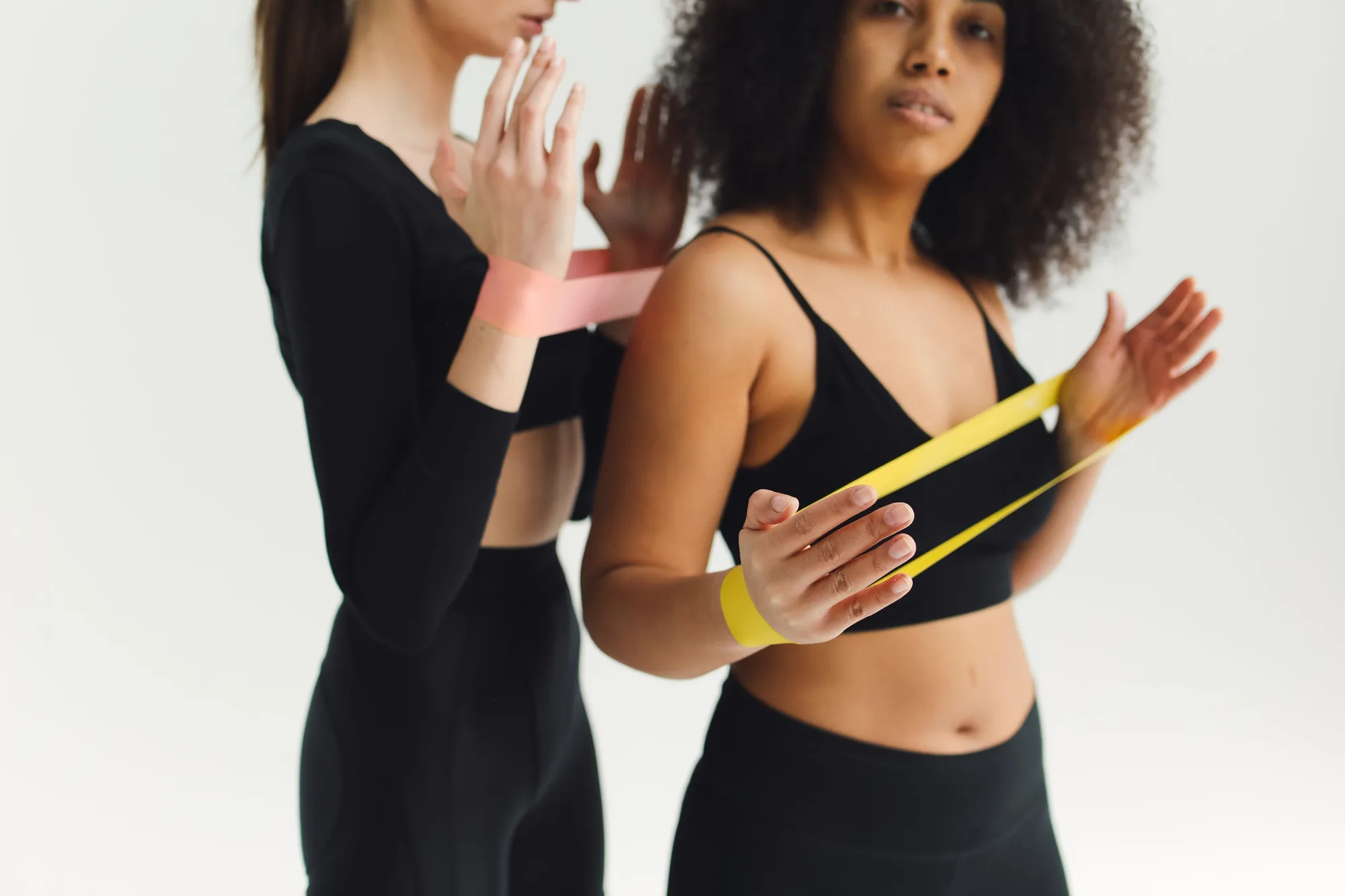 Two women using resistance bands in an exercise studio