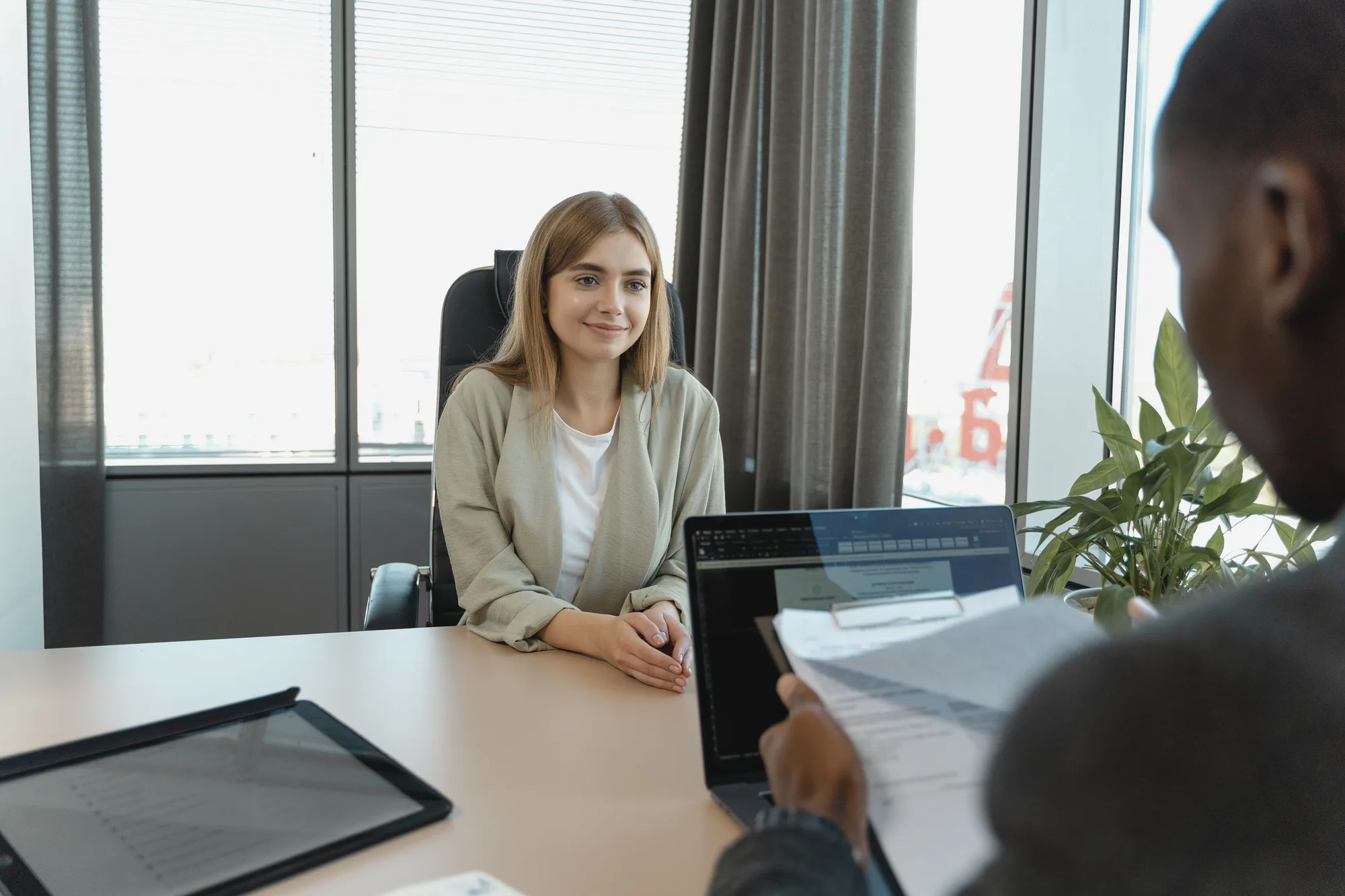 A woman speaking with another person across an office desk