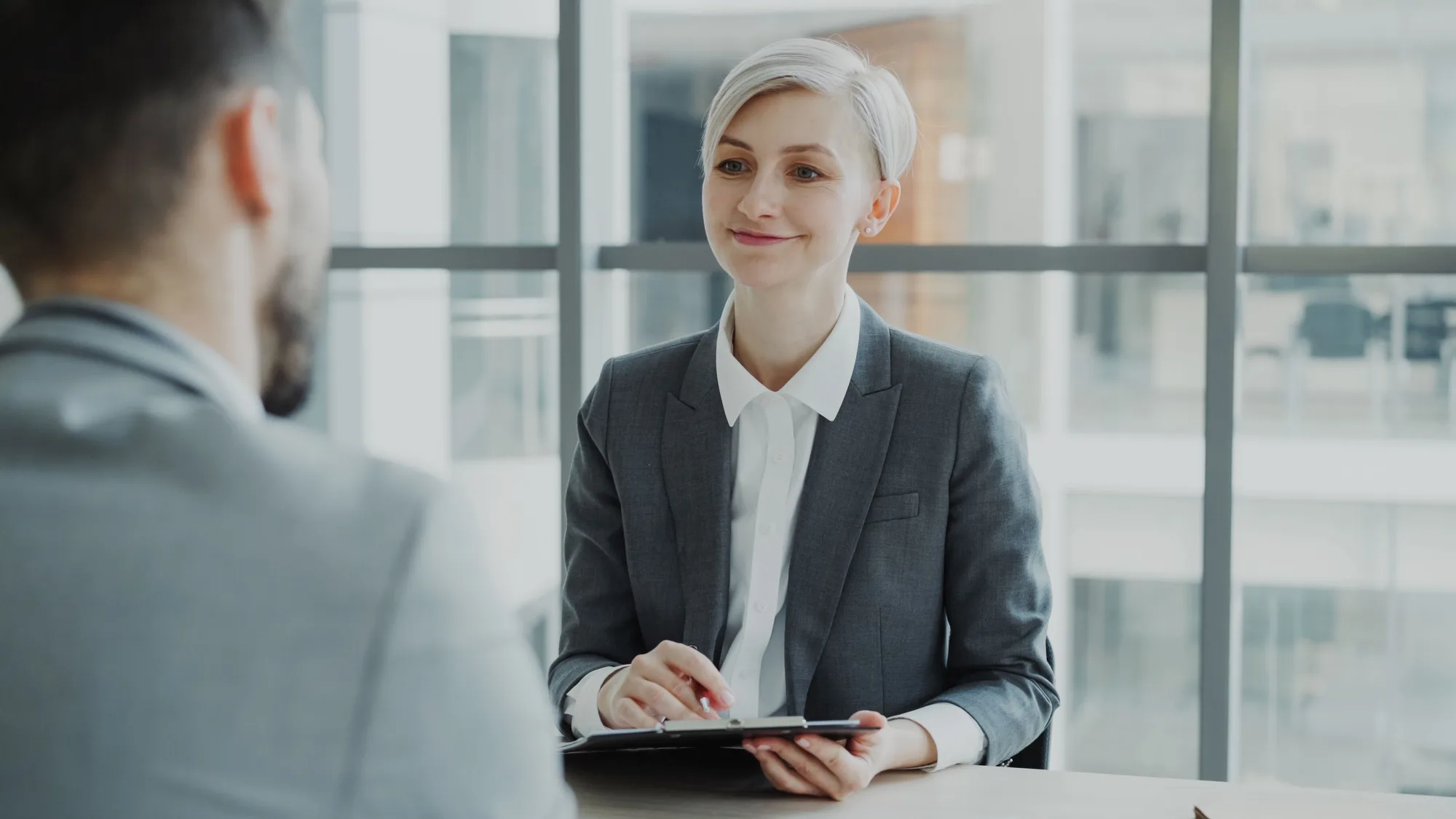 A woman speaking with a man across a table in a modern office