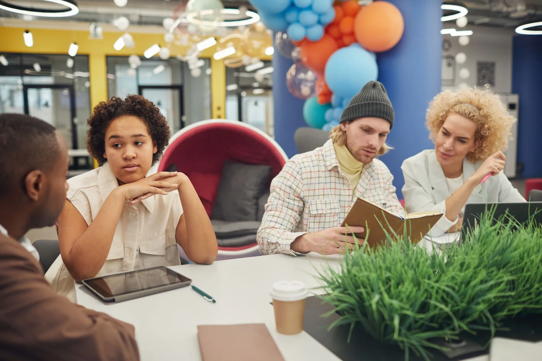 People discussing a project around a table in a bright shared workspace.