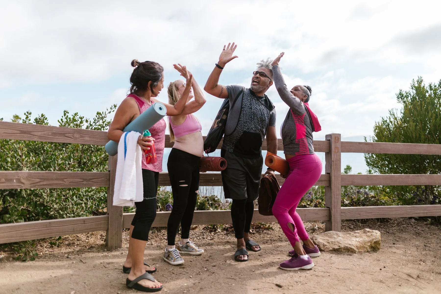 A group of older adults in sportswear sharing high fives outdoors.
