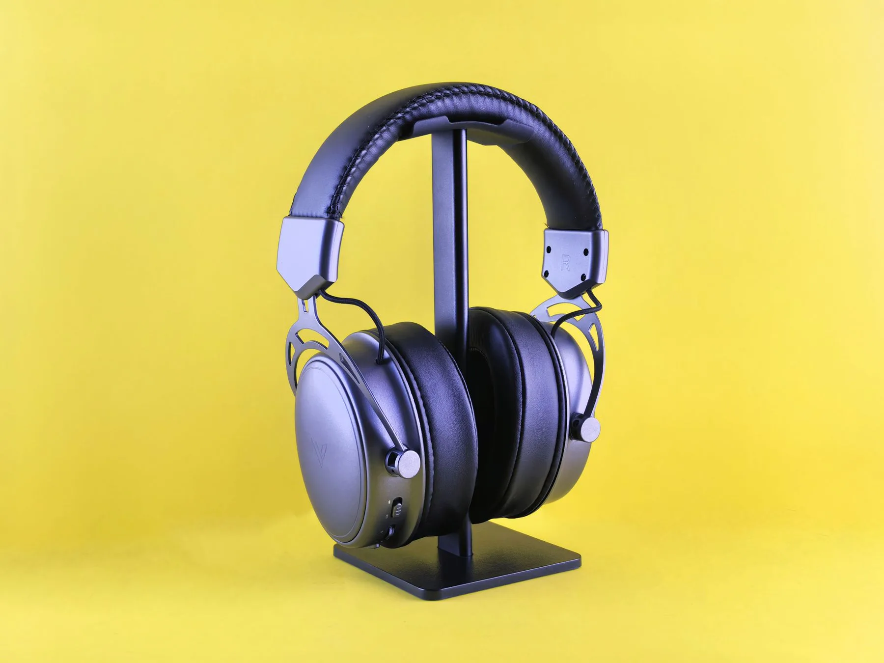 Headphones displayed on a stand against a yellow background