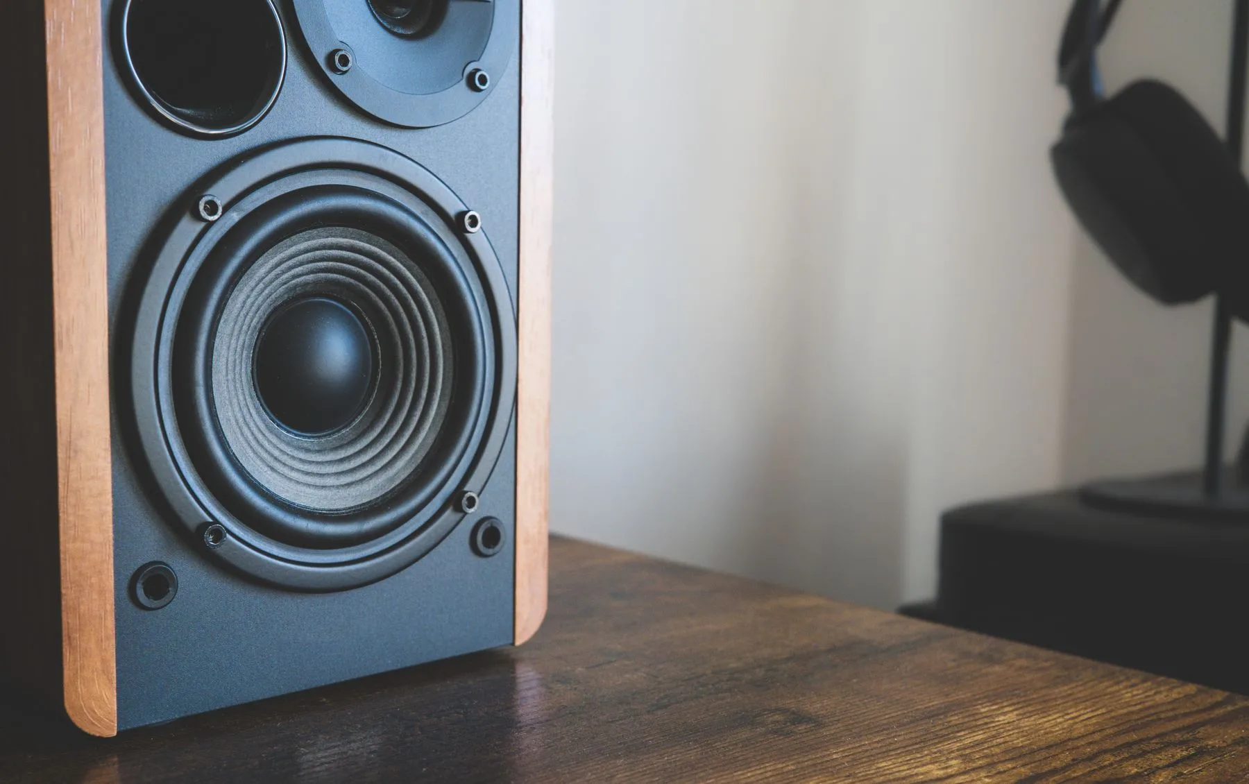 Speaker and headphones arranged on a wooden desk