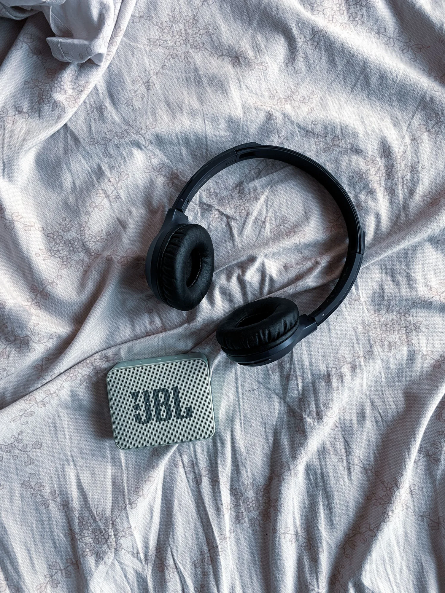 Portable speaker and headphones on grey fabric