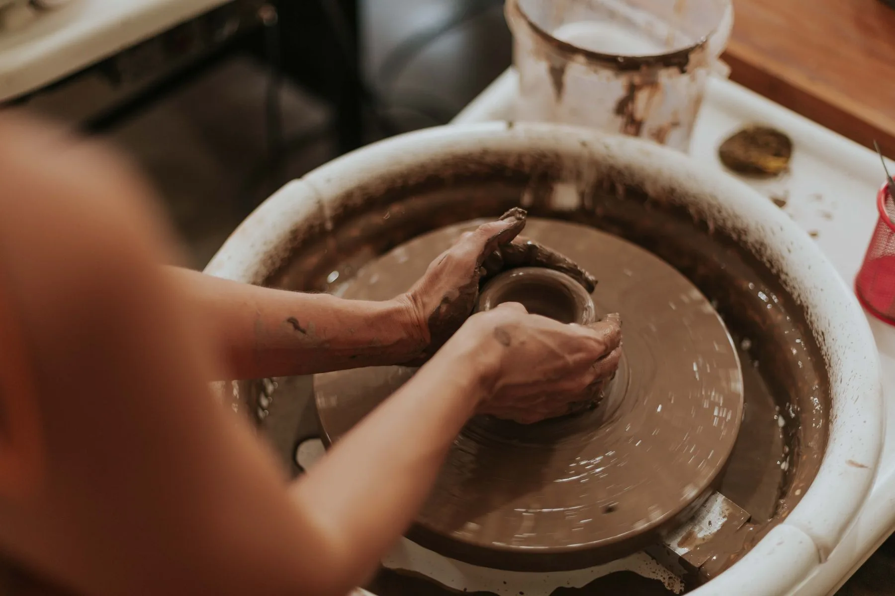 Hands shaping a clay bowl