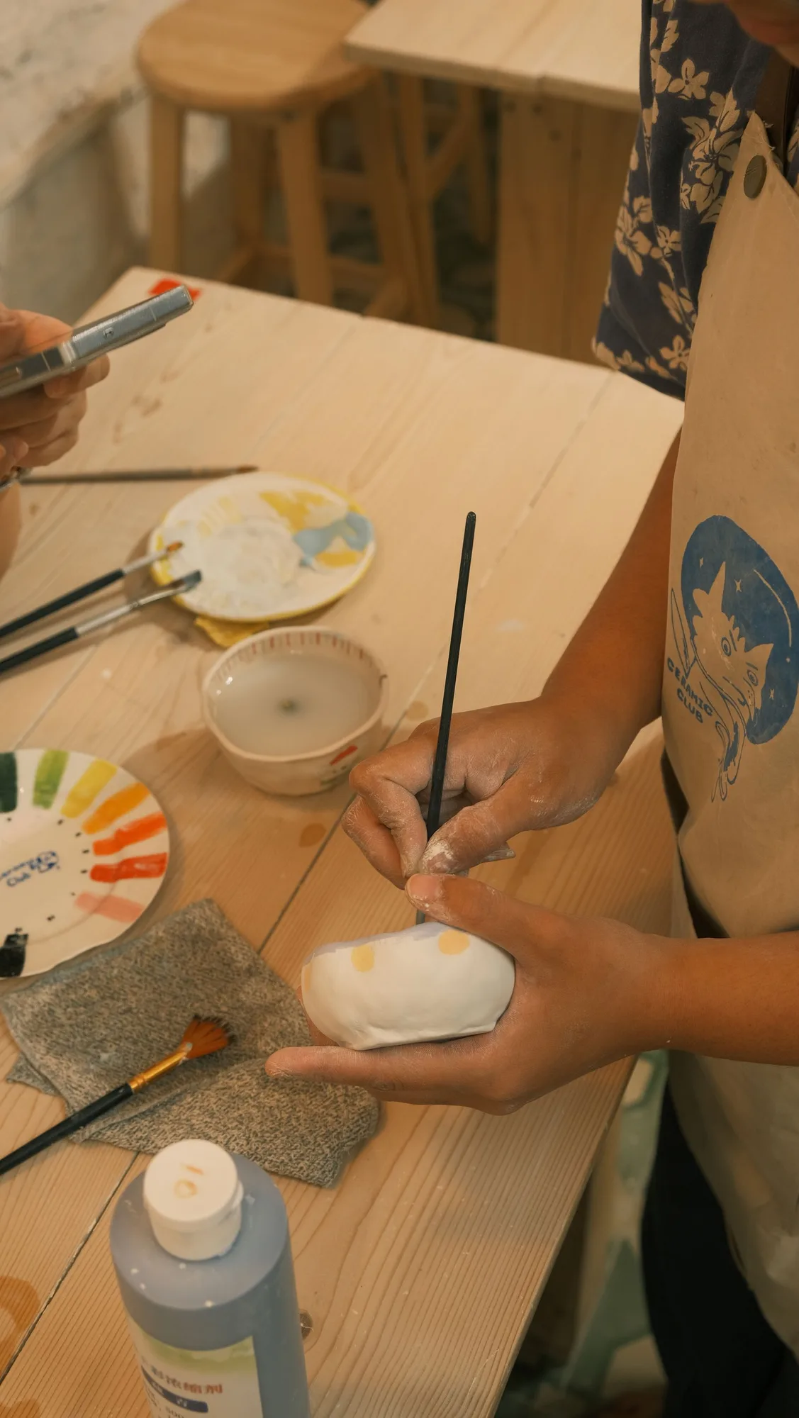 Hands painting a ceramic piece