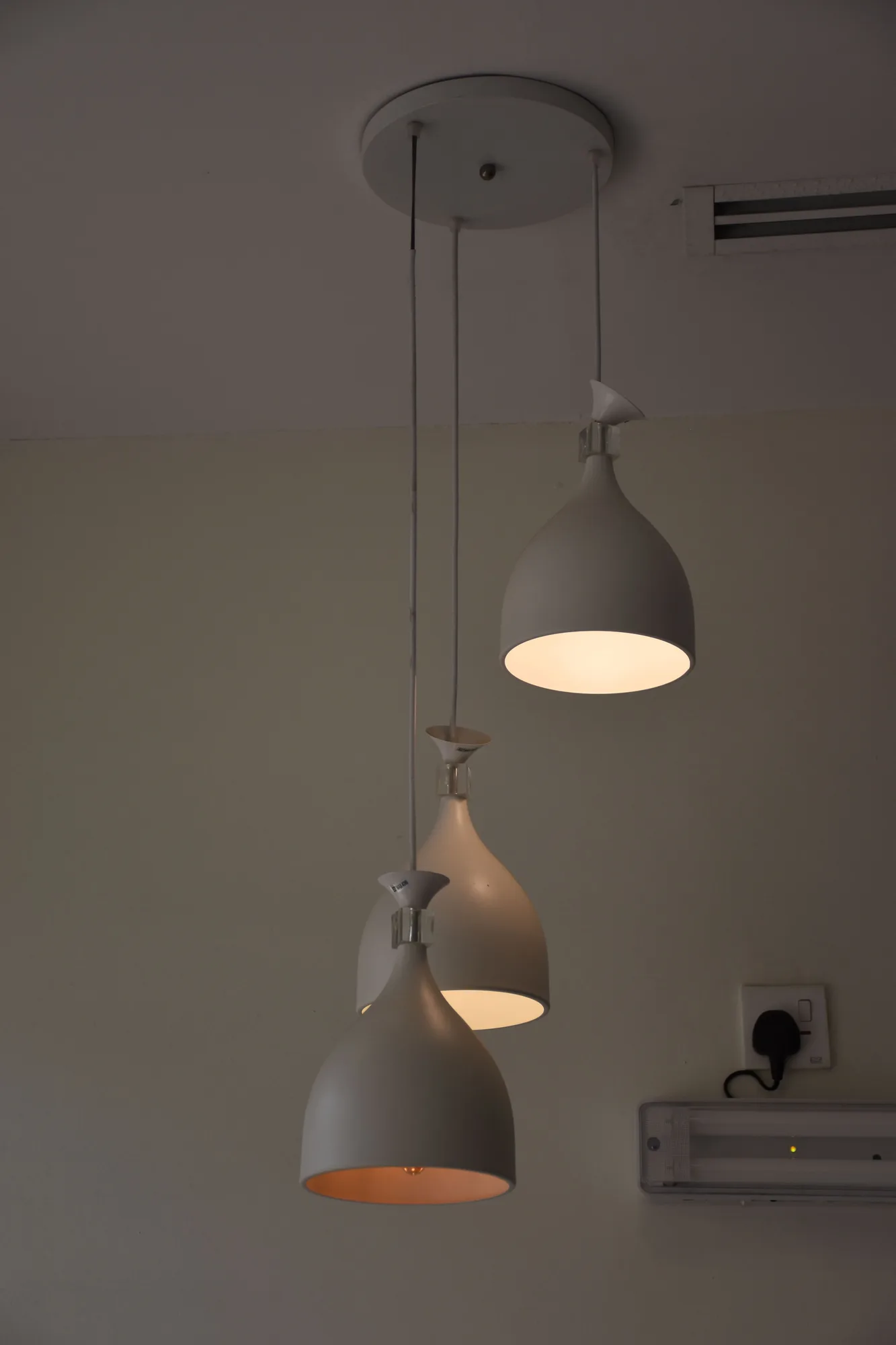 Three white pendant lights hanging in a modern interior