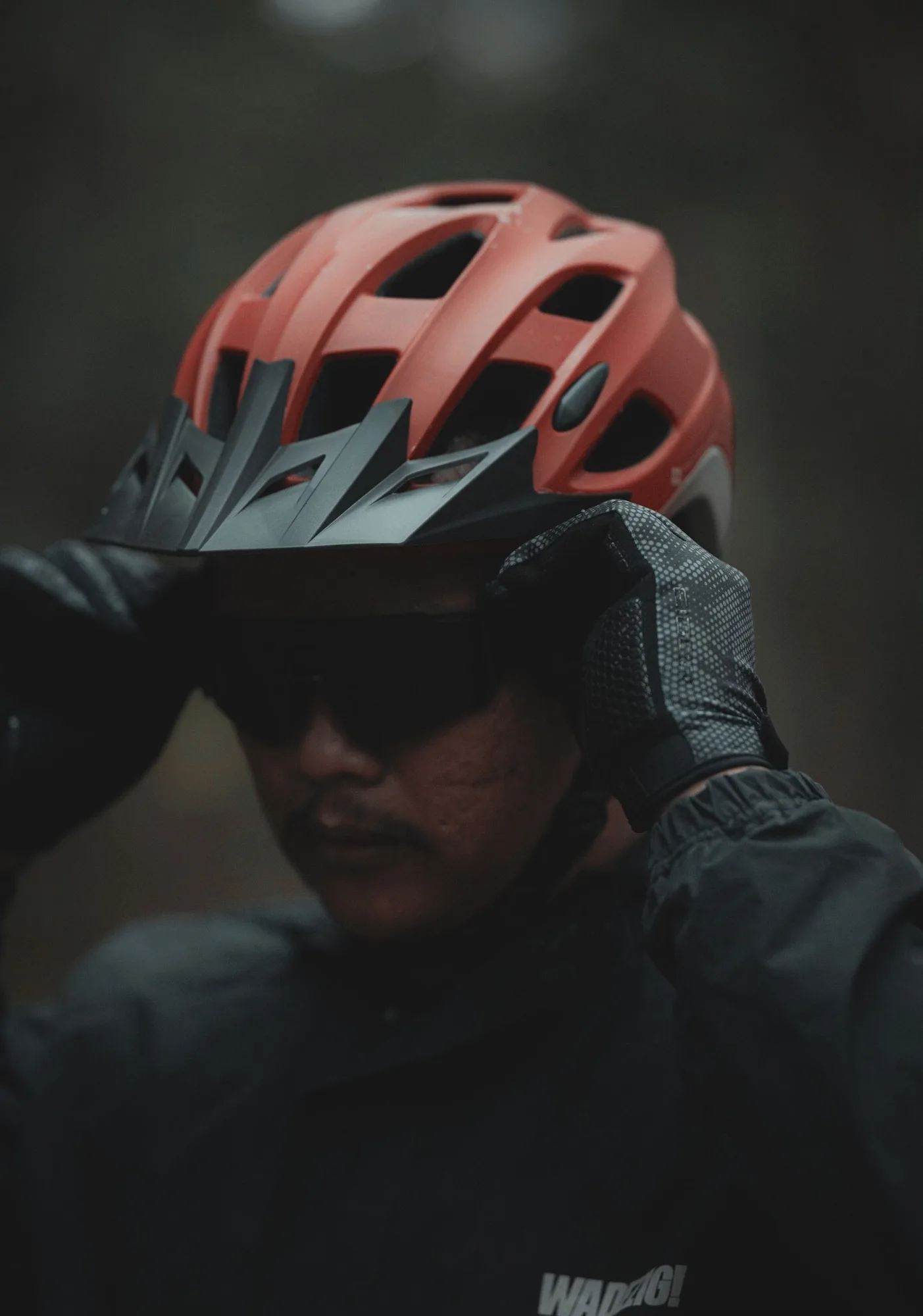 Cyclist adjusting a red helmet outdoors