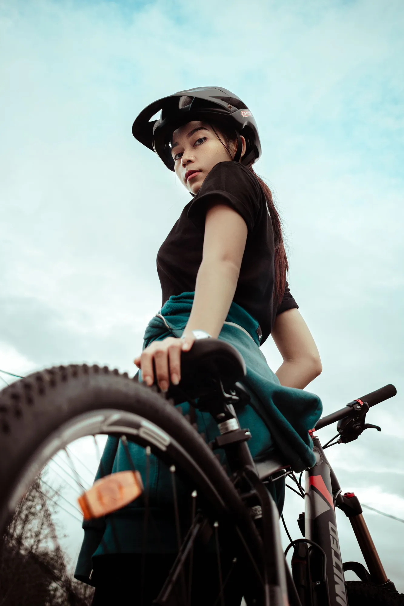 Woman wearing a helmet and standing with a bicycle outdoors
