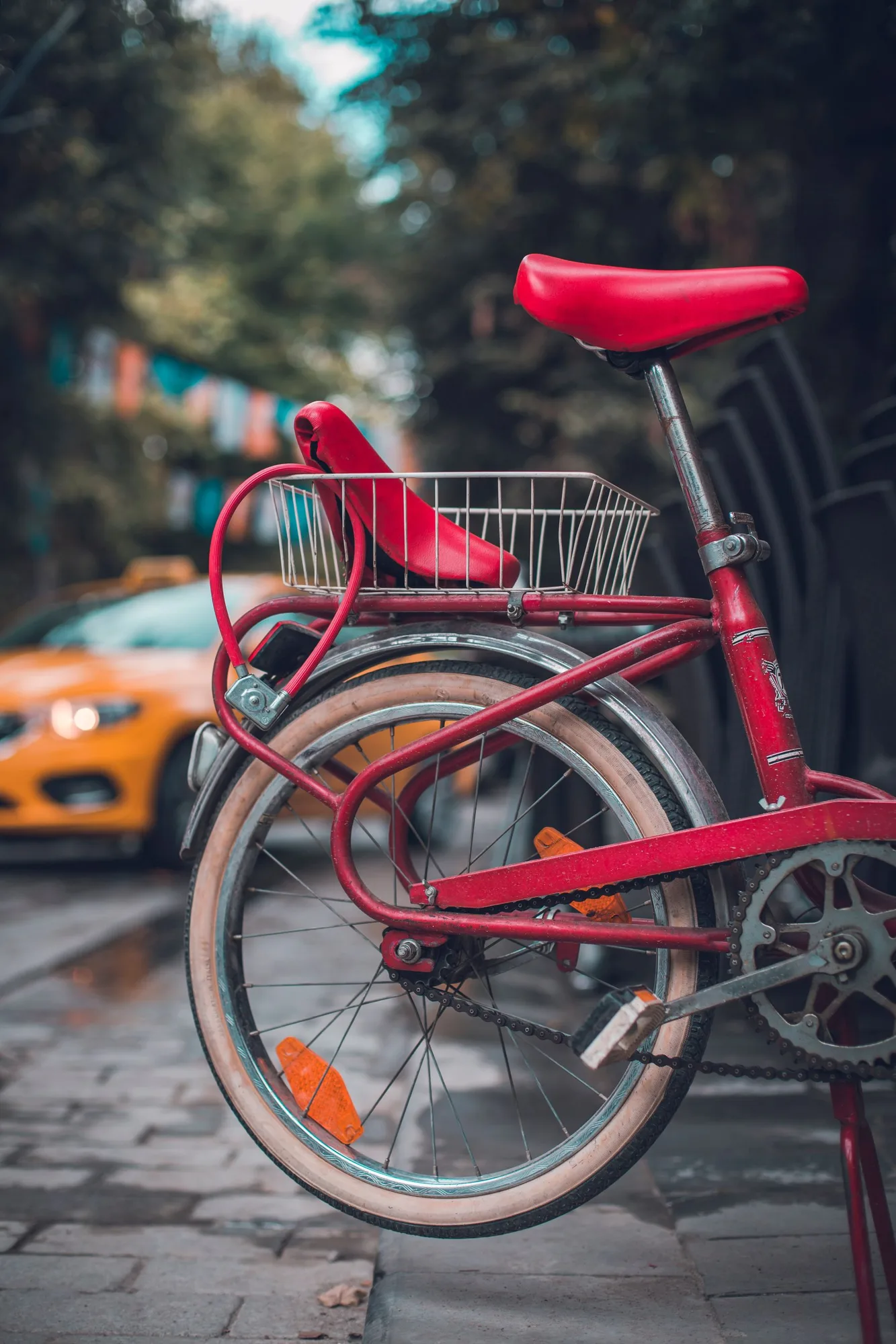 Red bicycle parked along a city street with a taxi behind it